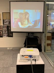 Steiner exhibit, a projector displaying an image of Steiner students working on a laptop