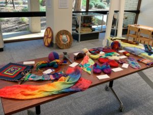 Table displaying knitted and material craft works created by Steiner students