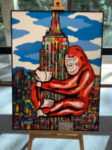 Colour woodcut artwork featuring a oversized gorilla hugging a large building