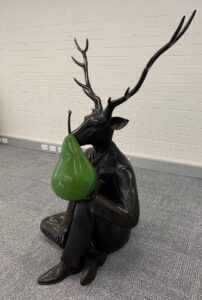 Bronze animal statue holding a green pear