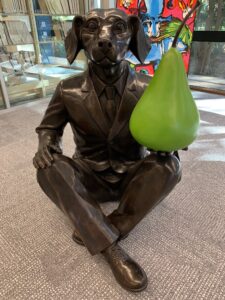 Bronze dog statue holding a green pear